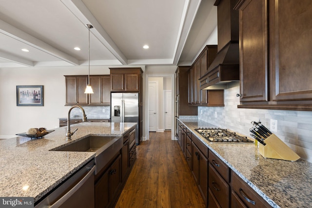 kitchen featuring dark wood-style flooring, stainless steel appliances, wall chimney exhaust hood, beam ceiling, and a sink