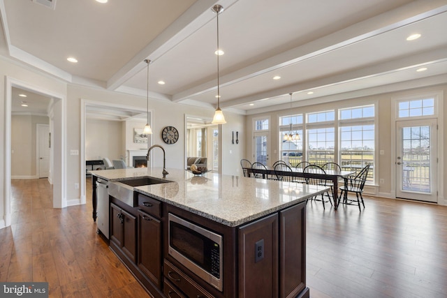 kitchen featuring dark wood-style flooring, stainless steel appliances, a lit fireplace, beamed ceiling, and dark brown cabinetry
