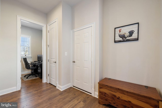 corridor featuring baseboards and dark wood-type flooring