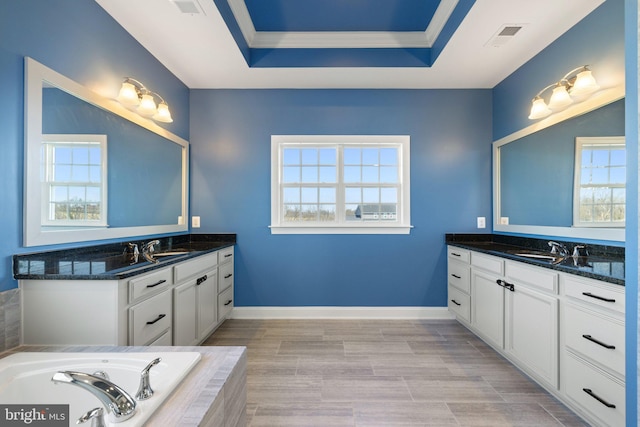 bathroom featuring baseboards, a sink, and two vanities