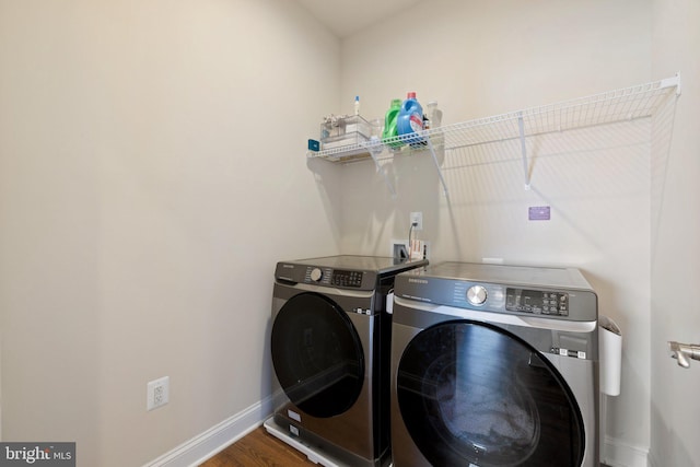 laundry area featuring washing machine and clothes dryer, baseboards, laundry area, and wood finished floors