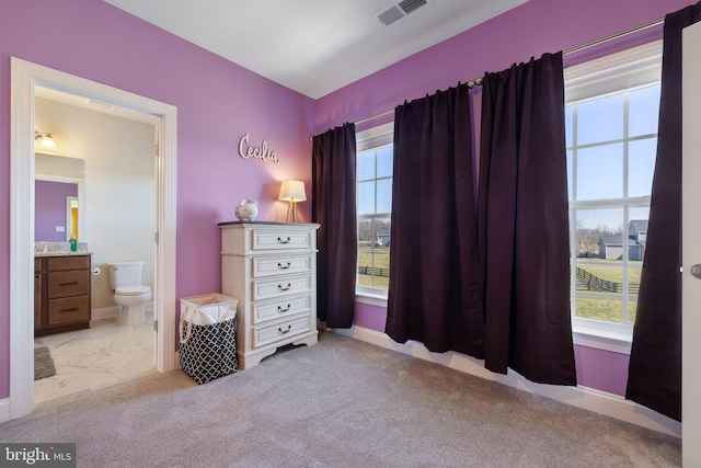 bedroom with ensuite bath, visible vents, multiple windows, and carpet