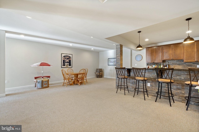 kitchen featuring a kitchen bar, tasteful backsplash, recessed lighting, light carpet, and brown cabinets