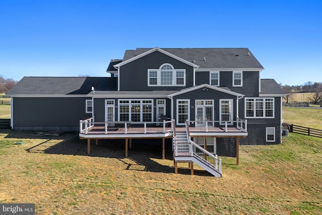 back of property featuring stairway, french doors, fence, a deck, and a lawn