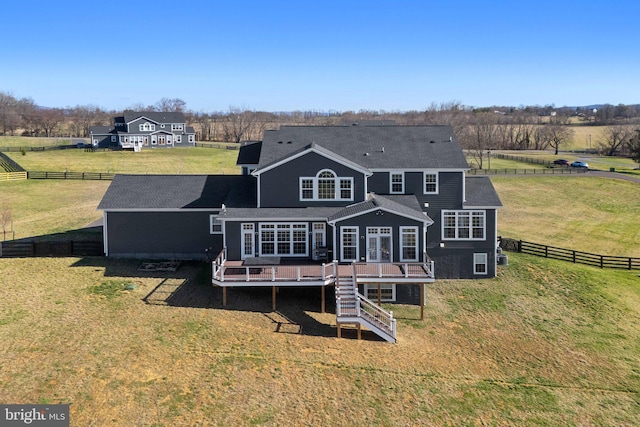 rear view of property with fence, stairs, a rural view, a deck, and a yard