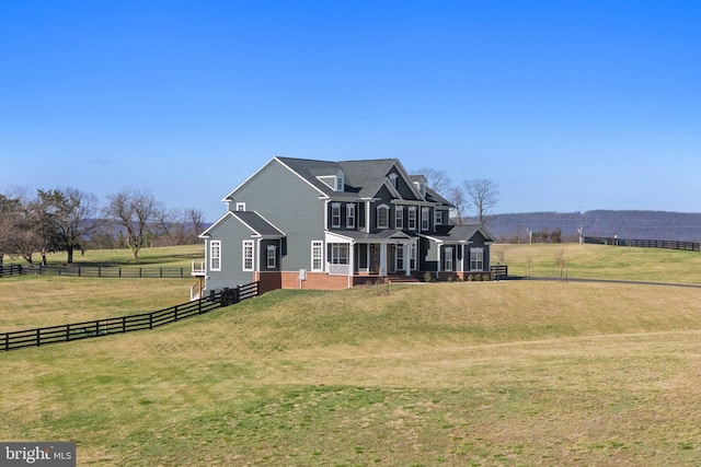 view of front of house featuring fence, a front lawn, and a rural view