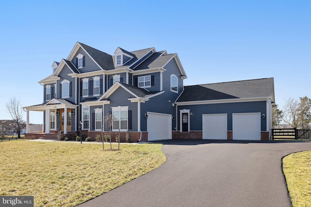 view of front of home with an attached garage, fence, brick siding, a front lawn, and aphalt driveway