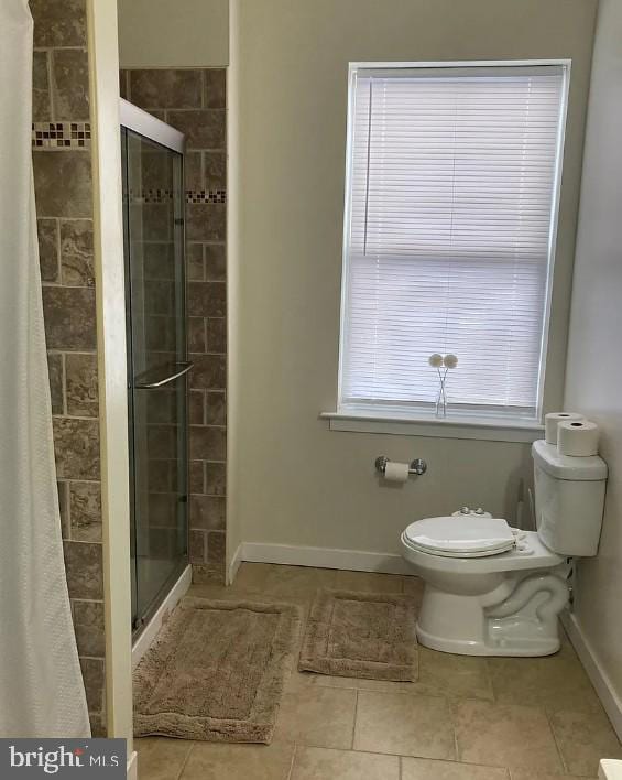 full bathroom featuring baseboards, toilet, a stall shower, and tile patterned flooring