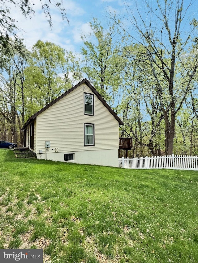 view of side of home with a lawn and fence