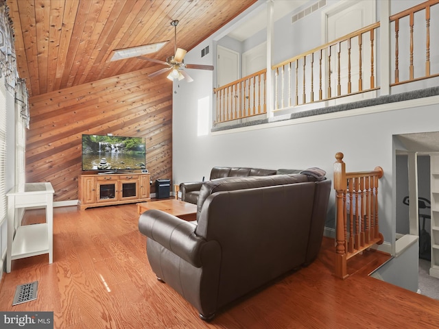living room featuring visible vents, ceiling fan, wooden walls, and wooden ceiling