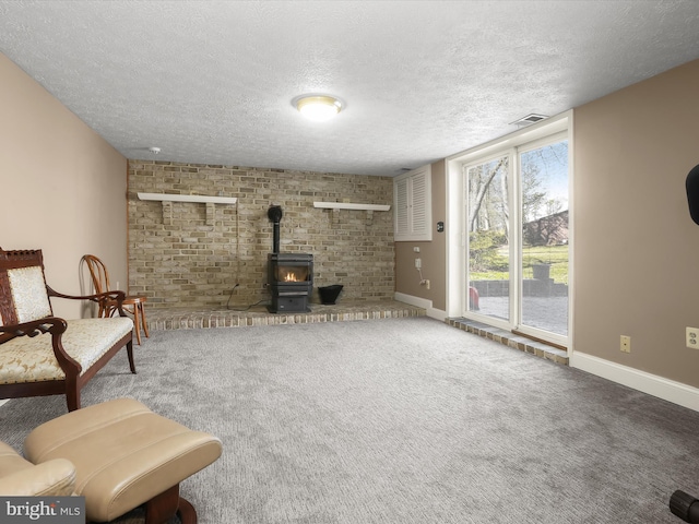 living room featuring visible vents, a wood stove, baseboards, a textured ceiling, and carpet flooring