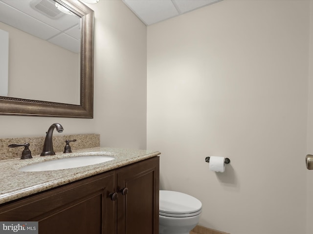 bathroom featuring vanity, a drop ceiling, and toilet