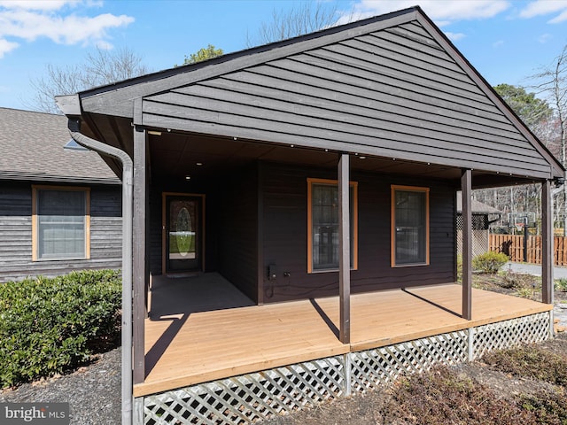 back of house featuring fence and roof with shingles