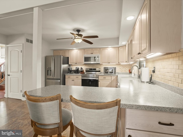 kitchen featuring stainless steel appliances, a ceiling fan, decorative backsplash, and a sink