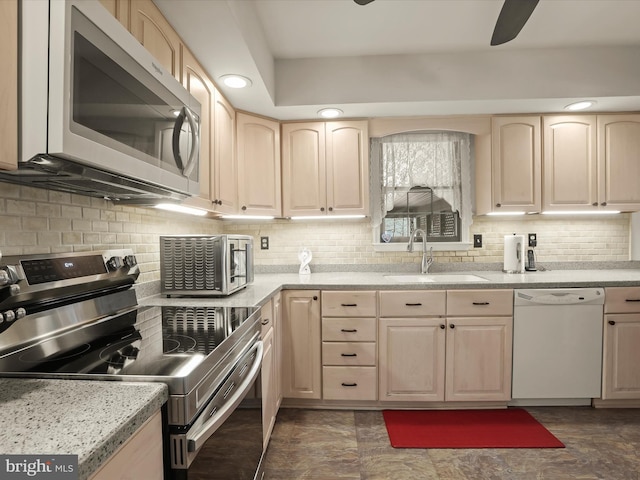 kitchen with a sink, light brown cabinets, white appliances, a ceiling fan, and backsplash