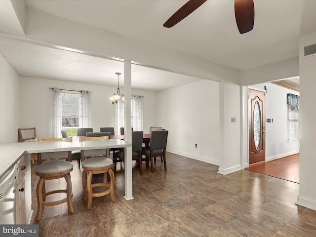 dining space with baseboards and ceiling fan with notable chandelier