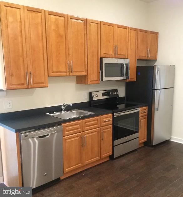 416 N Wiota St, Philadelphia, PA 19104 - kitchen with a sink, dark countertops, appliances with stainless steel finishes, and dark wood finished floors