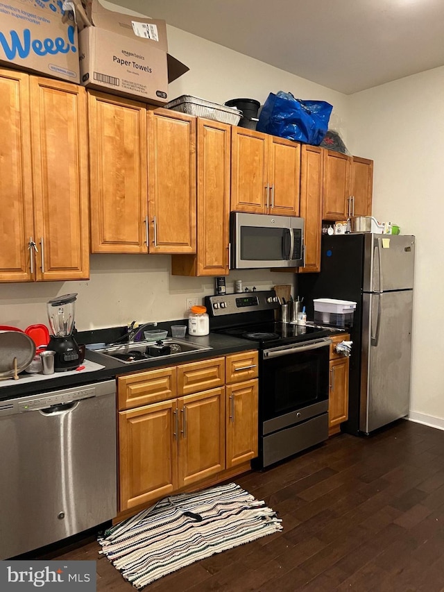 416 N Wiota St, Philadelphia, PA 19104 - kitchen featuring stainless steel appliances, a sink, dark countertops, dark wood-style floors, and brown cabinets