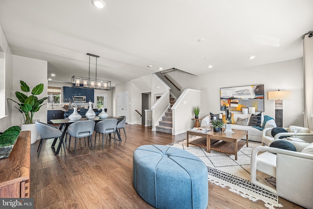 living room with a notable chandelier, recessed lighting, wood finished floors, and stairway