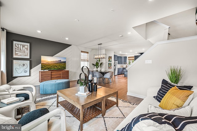 living area with stairs, a chandelier, wood finished floors, baseboards, and recessed lighting