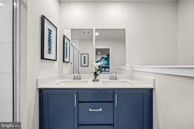 bathroom with double vanity, visible vents, a sink, and a shower with shower door