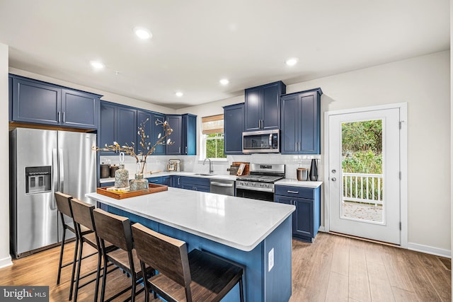 kitchen with light countertops, tasteful backsplash, stainless steel appliances, light wood-style floors, and blue cabinetry