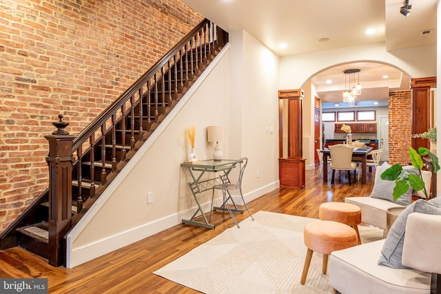 living room with baseboards, stairway, arched walkways, and wood finished floors