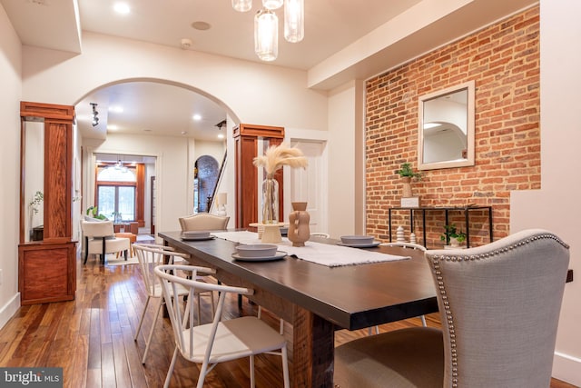 dining space with arched walkways and hardwood / wood-style flooring