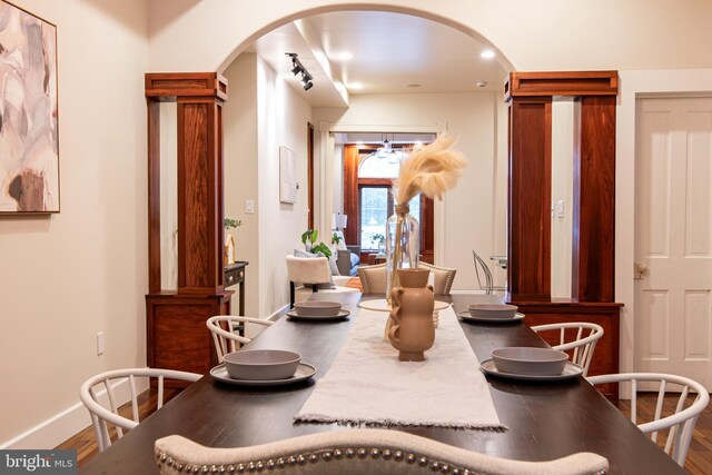 dining space with baseboards, arched walkways, and wood finished floors