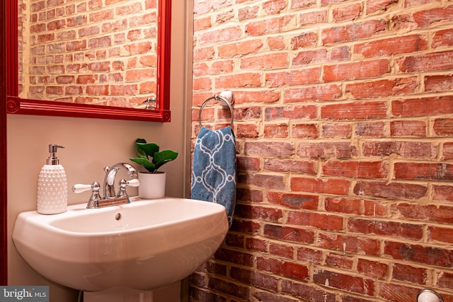 bathroom with brick wall and a sink
