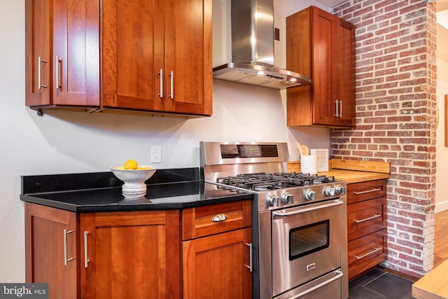 kitchen featuring range hood, brown cabinetry, stainless steel gas stove, and dark tile patterned flooring