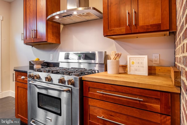 kitchen featuring baseboards, exhaust hood, gas range, brown cabinets, and wood counters