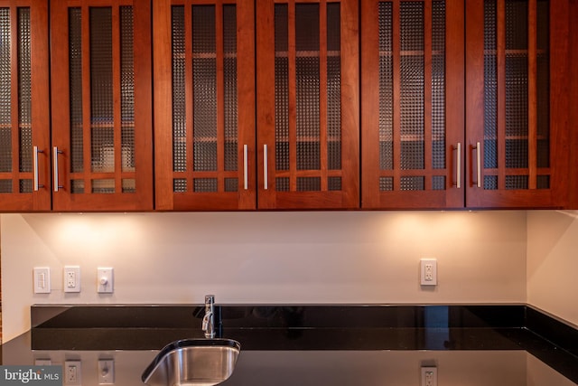kitchen with brown cabinets, a sink, and glass insert cabinets