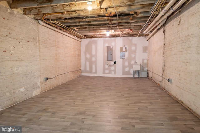 unfinished below grade area with electric panel and wood finished floors