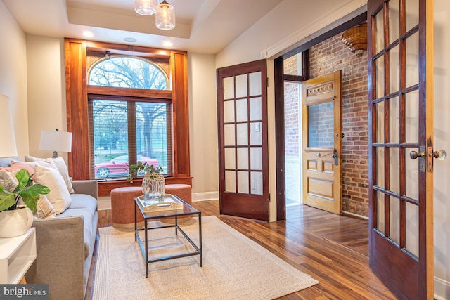 sitting room featuring french doors, wood finished floors, and a tray ceiling