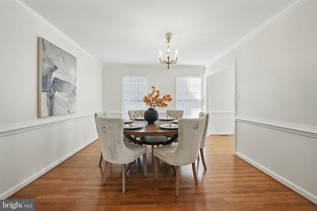 dining space featuring crown molding, an inviting chandelier, and wood finished floors