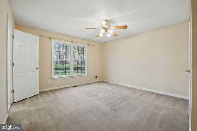 carpeted spare room featuring baseboards and a ceiling fan