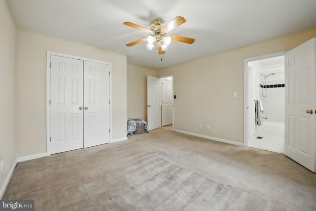 unfurnished bedroom featuring a closet, baseboards, ensuite bathroom, a ceiling fan, and carpet floors