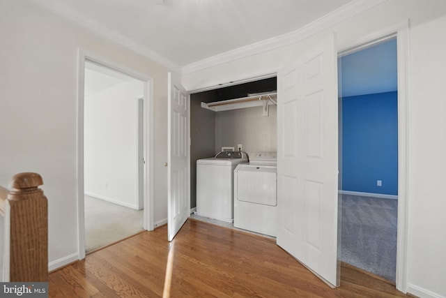 laundry room with laundry area, crown molding, wood finished floors, washing machine and clothes dryer, and baseboards