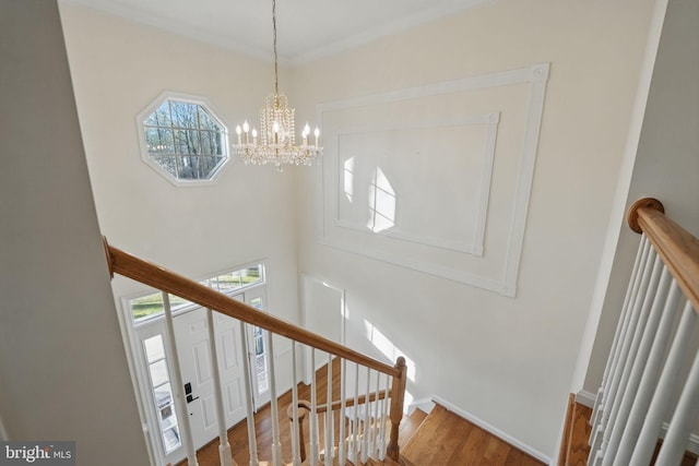 staircase featuring baseboards, a chandelier, and wood finished floors