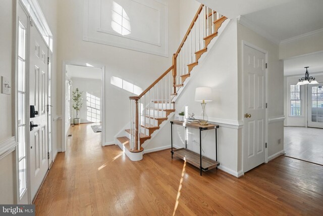 entryway featuring light wood-style flooring, crown molding, and stairs