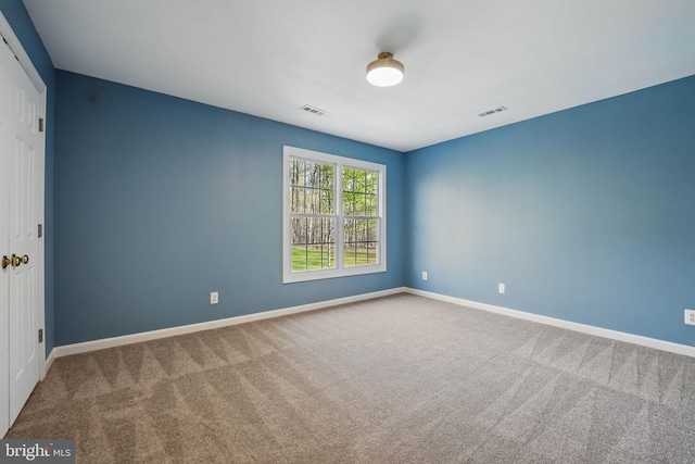 carpeted spare room with visible vents and baseboards