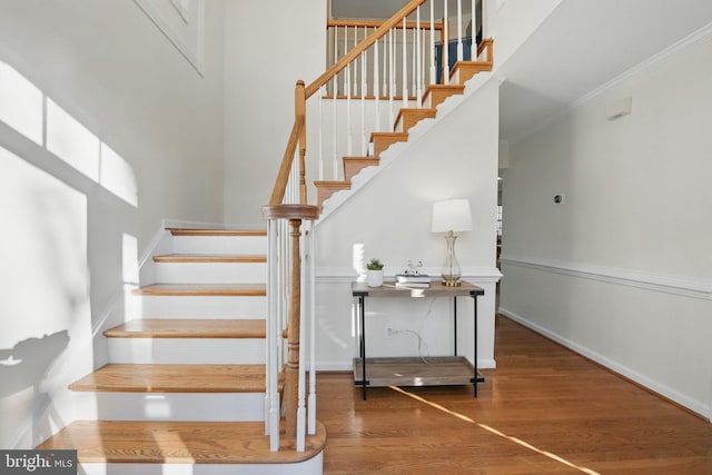 staircase featuring ornamental molding, baseboards, and wood finished floors