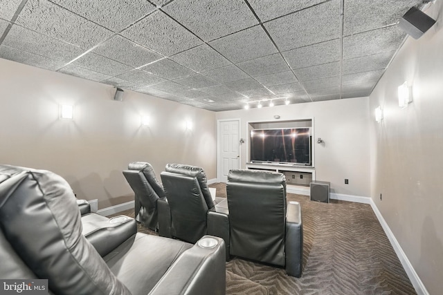 carpeted home theater room with baseboards, rail lighting, and a paneled ceiling