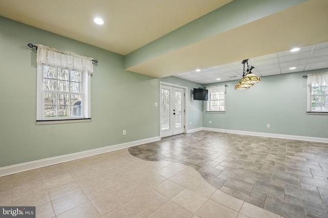 empty room featuring baseboards, recessed lighting, a paneled ceiling, and a healthy amount of sunlight