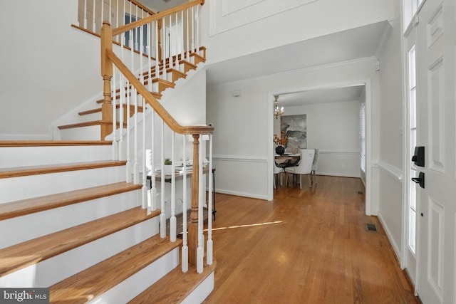 foyer featuring stairs, visible vents, crown molding, and wood finished floors