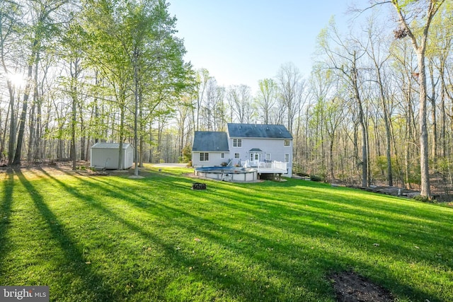back of property with an outbuilding, a deck, a lawn, and a storage unit
