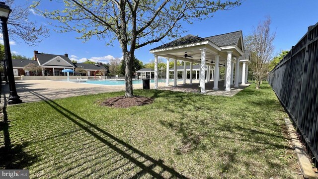 view of yard featuring a ceiling fan, an outdoor pool, and fence