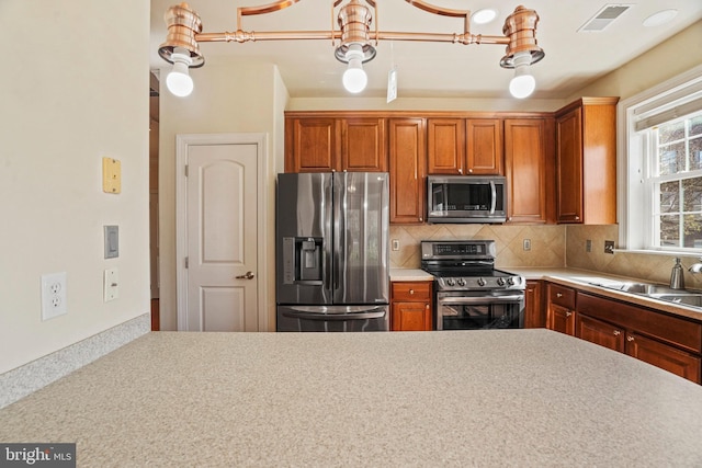 kitchen featuring tasteful backsplash, a sink, light countertops, appliances with stainless steel finishes, and visible vents