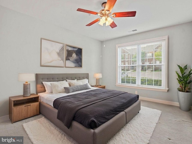 bedroom featuring baseboards, visible vents, a ceiling fan, and light colored carpet